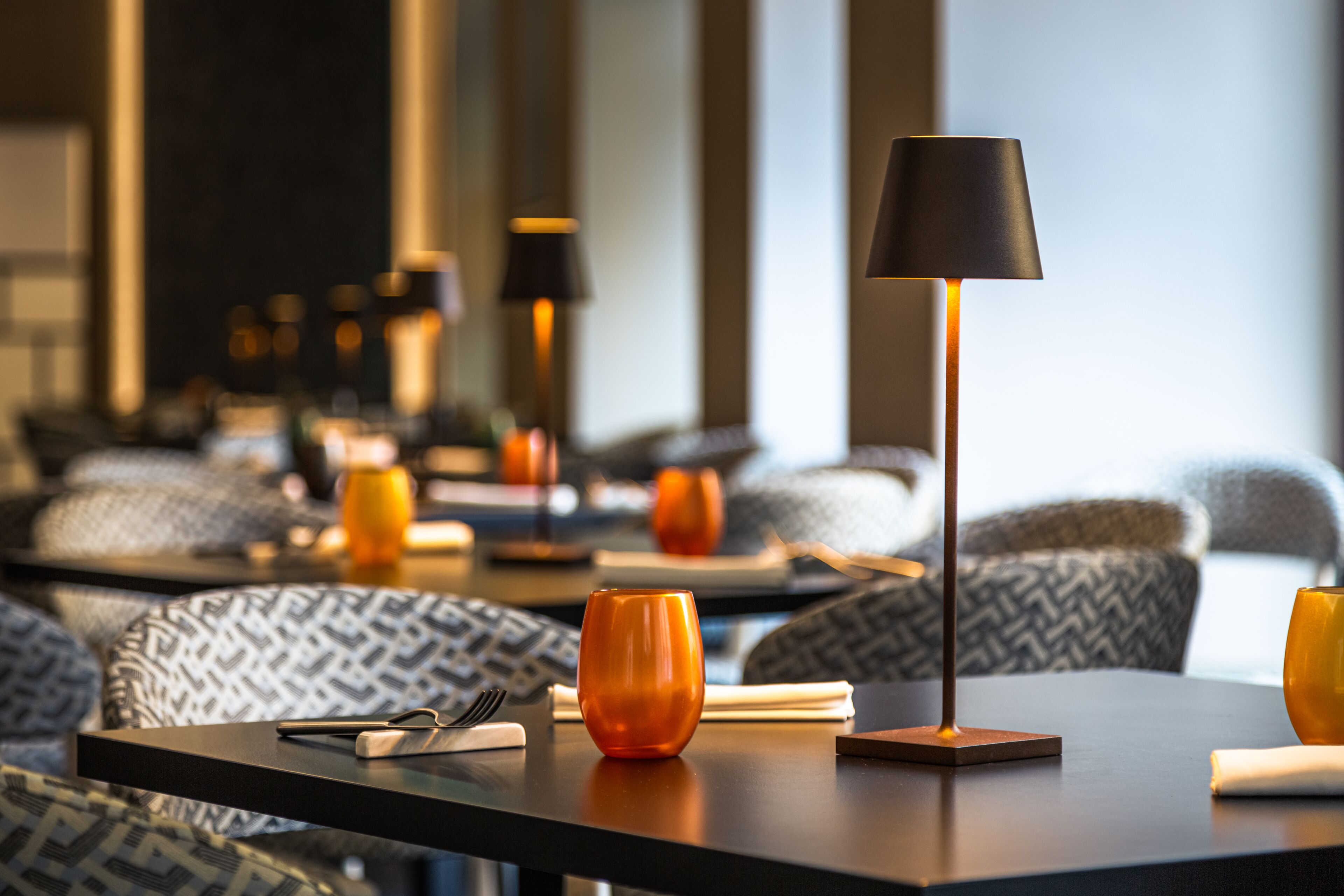 A modern hotel room with a sofa, a coffee table, and a lamp.