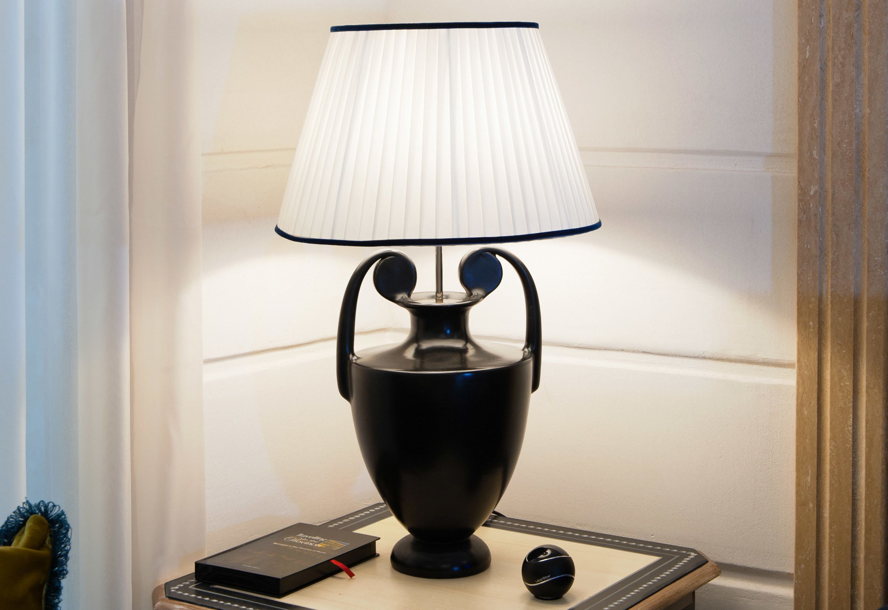Una lampada da tavolo nera con paralume bianco su un comodino.