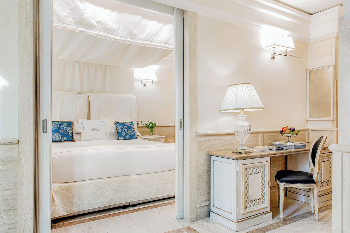 A bedroom with a bed, bedside table, lamp, and a chair.