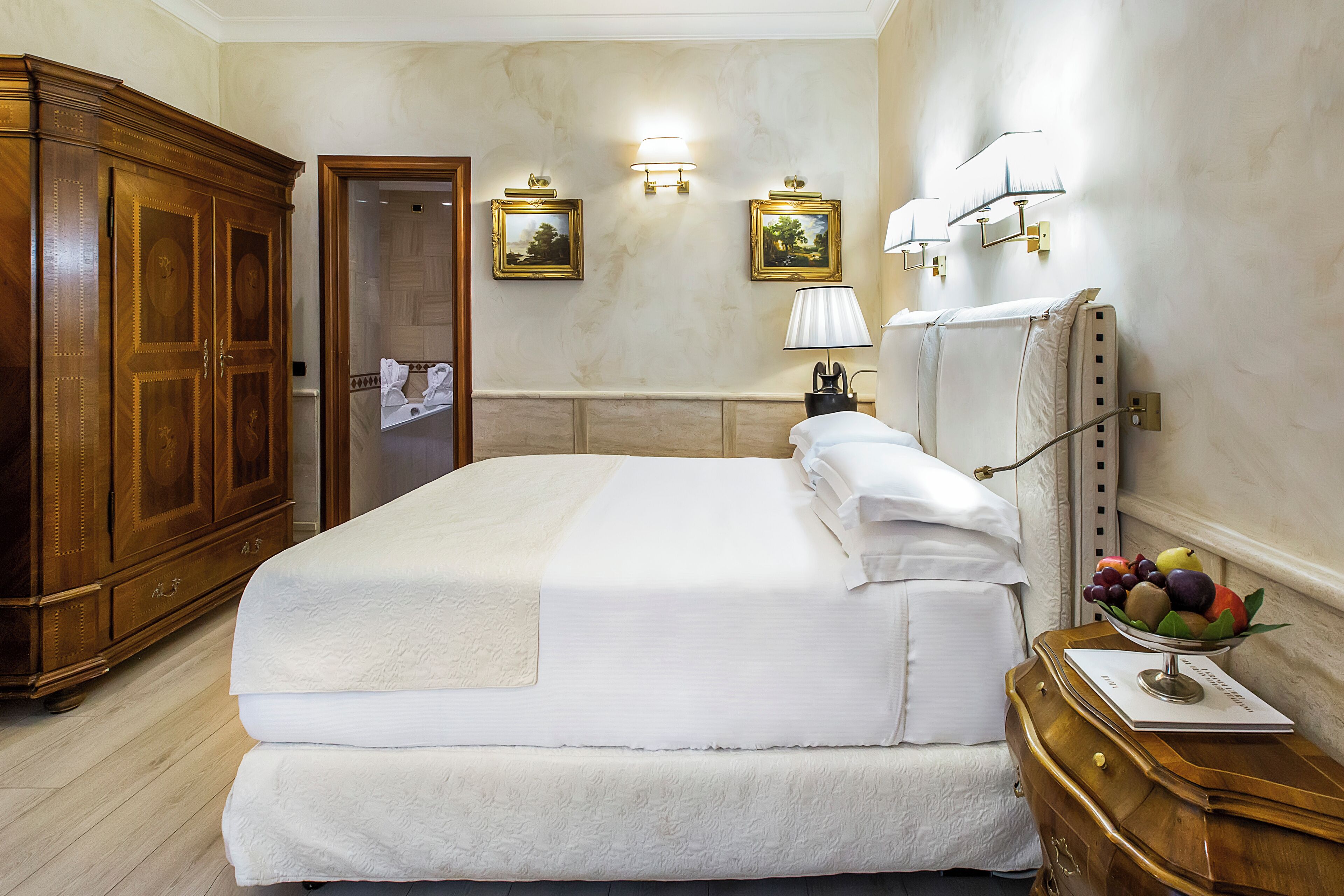 Camera d'albergo con un letto grande, un armadio in legno, uno specchio e lampade a parete.