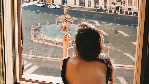 A view from a window of a building with a fountain in the center of a square, surrounded by historic architecture. - Hotel Barocco (Rome)