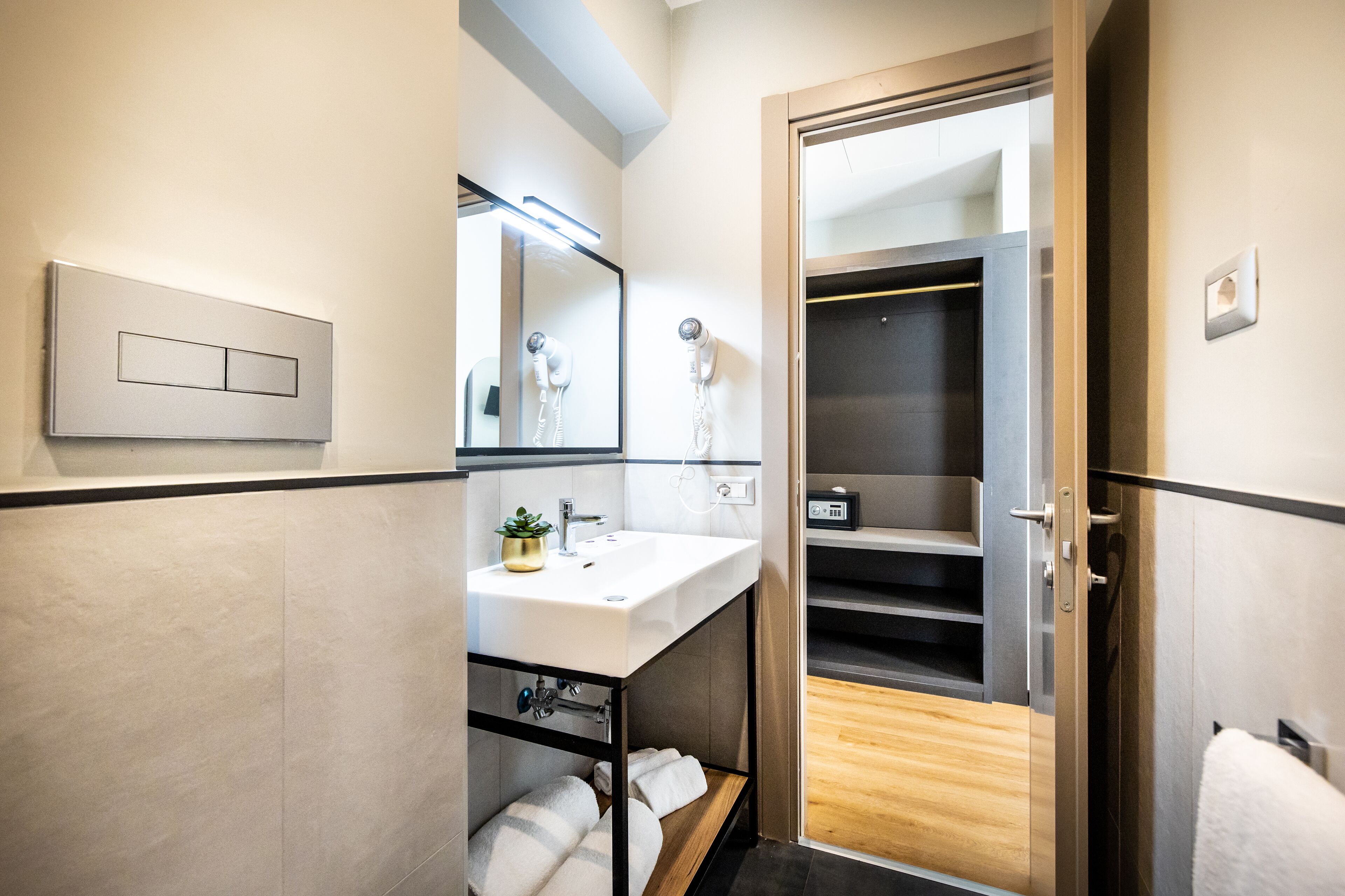 A modern bathroom with a white sink, a mirror, a hairdryer, and a towel rack.