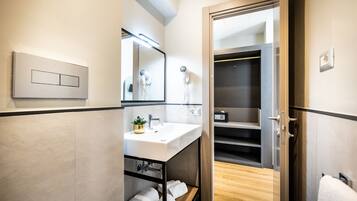A modern bathroom with a white sink, a mirror, a hairdryer, and a towel rack.