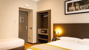 Een hotelkamer met twee bedden, een inloopkast, een nachtkastje met een lamp en een lijst aan de muur.