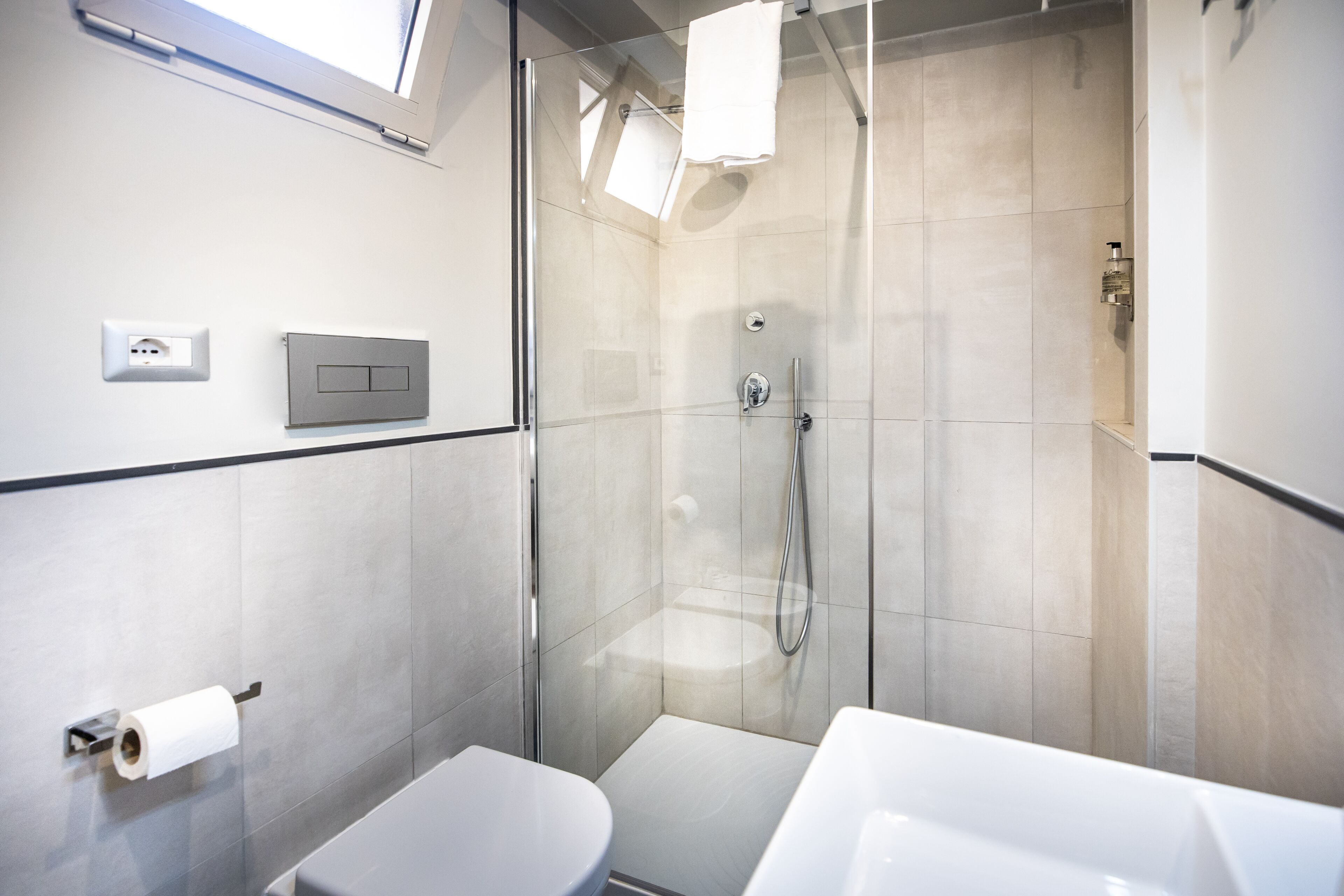 A modern bathroom with a glass-enclosed shower, a toilet, and a sink.