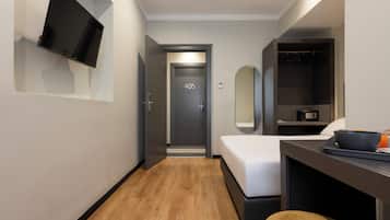 A modern hotel room with a bed, a desk with a bowl and orange drink, a TV mounted on the wall, and a door marked with the number 405.