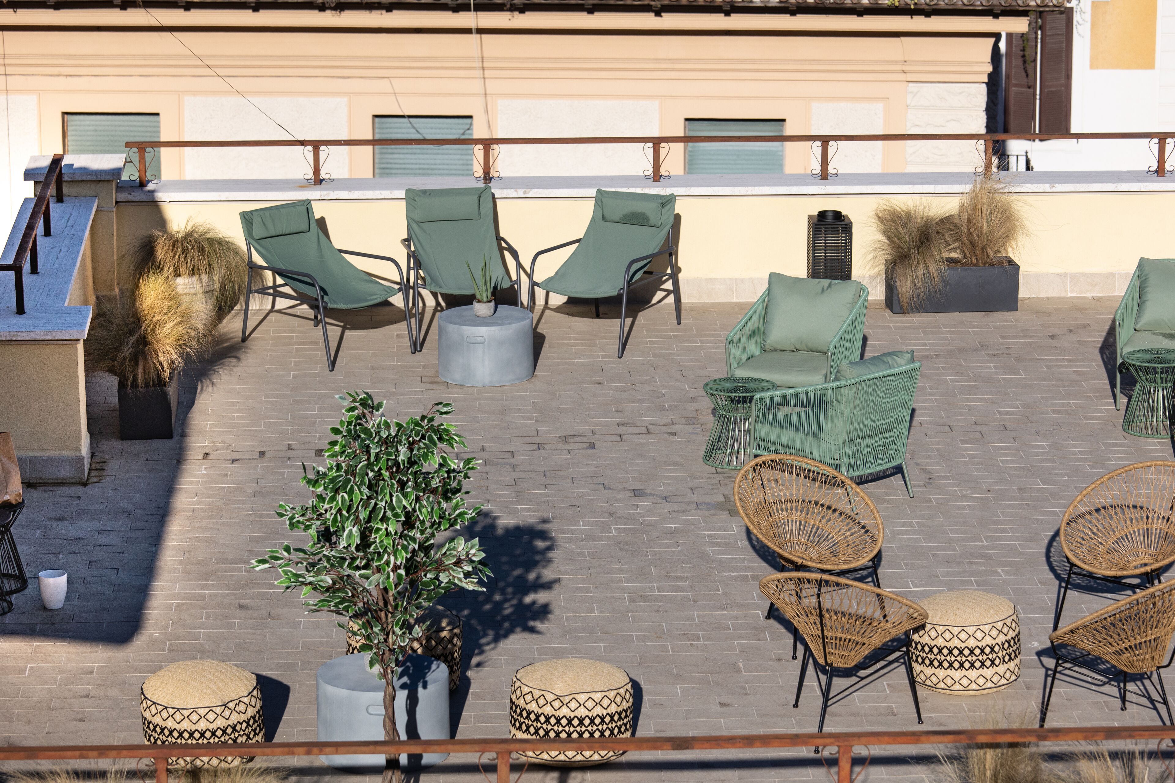 An outdoor seating area with wicker chairs and tables, a small tree, and a potted plant.