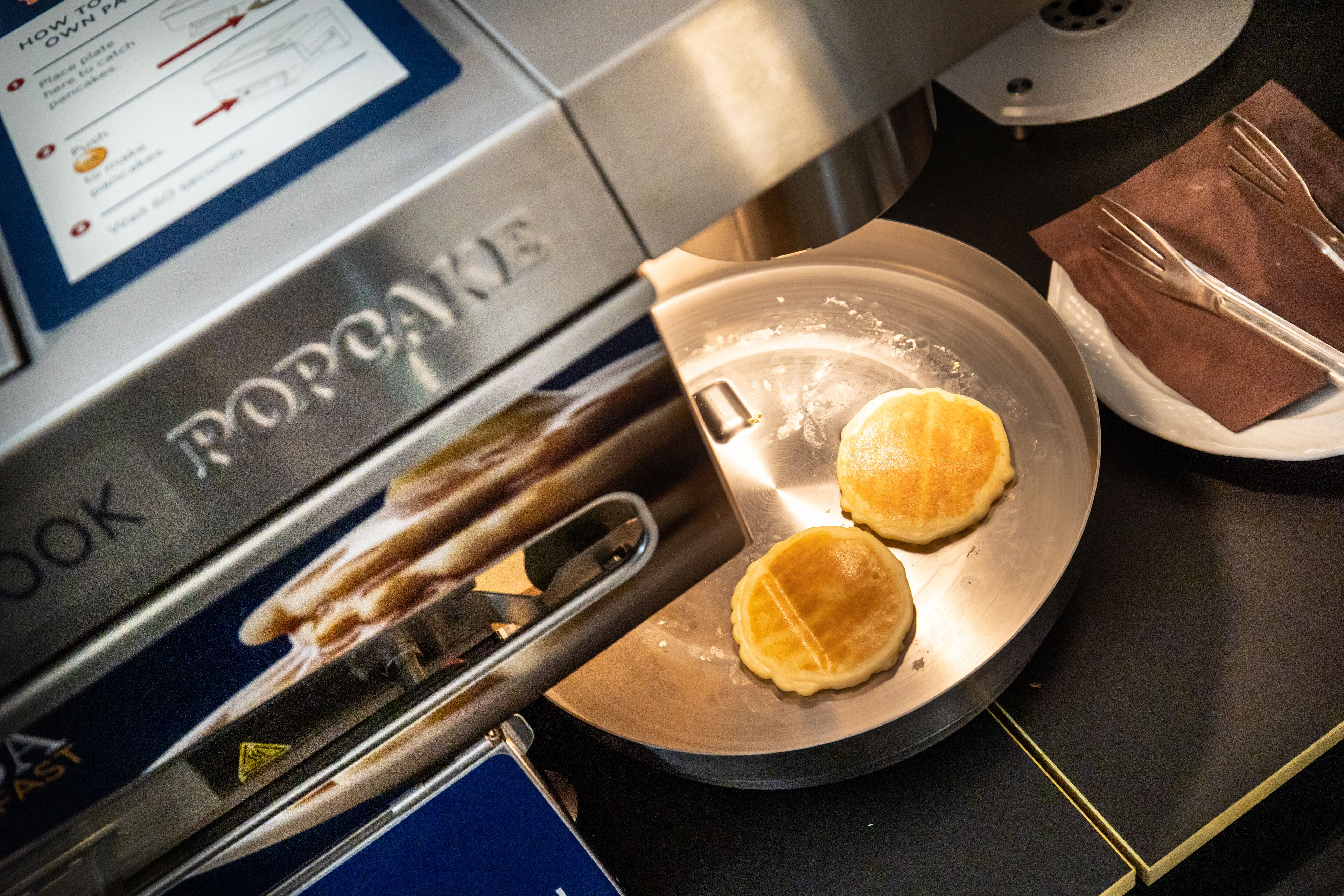 A kitchen with a toaster oven and a plate with two pancakes.