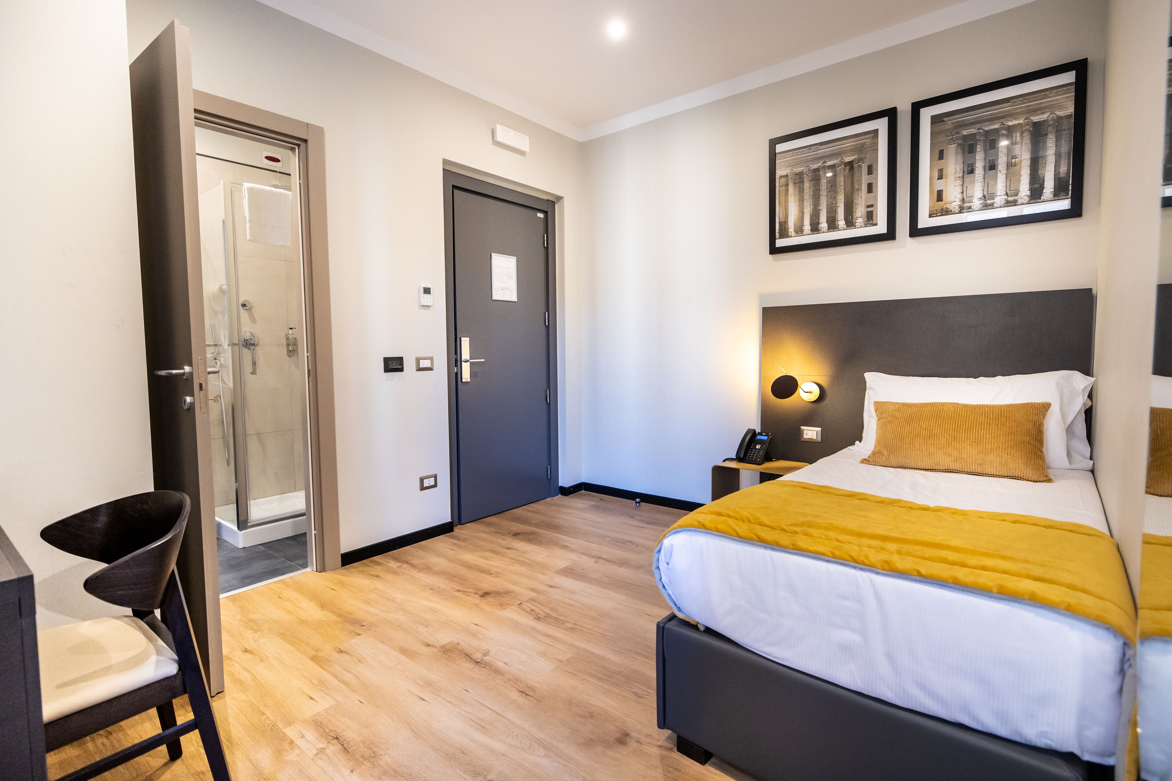 A modern hotel room with a bed, bedside table, and a chair.