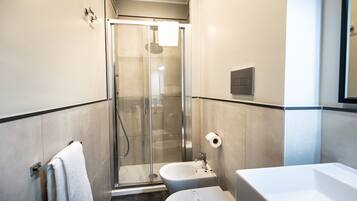 Uma casa de banho moderna com chuveiro em cabine de vidro, lavatório branco e sanita.