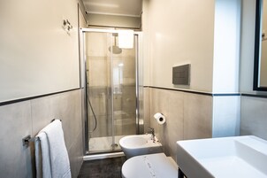 A modern bathroom with a glass-enclosed shower, a white sink, and a toilet.