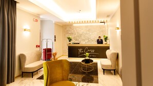 Uma área de recepção de hotel com balcão de atendimento, duas poltronas, uma mesa de centro e um mapa na parede.