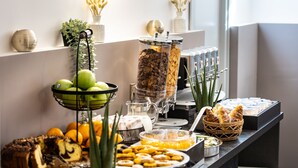 Buffet com diversas opções de comida, incluindo frutas, doces e bebidas.