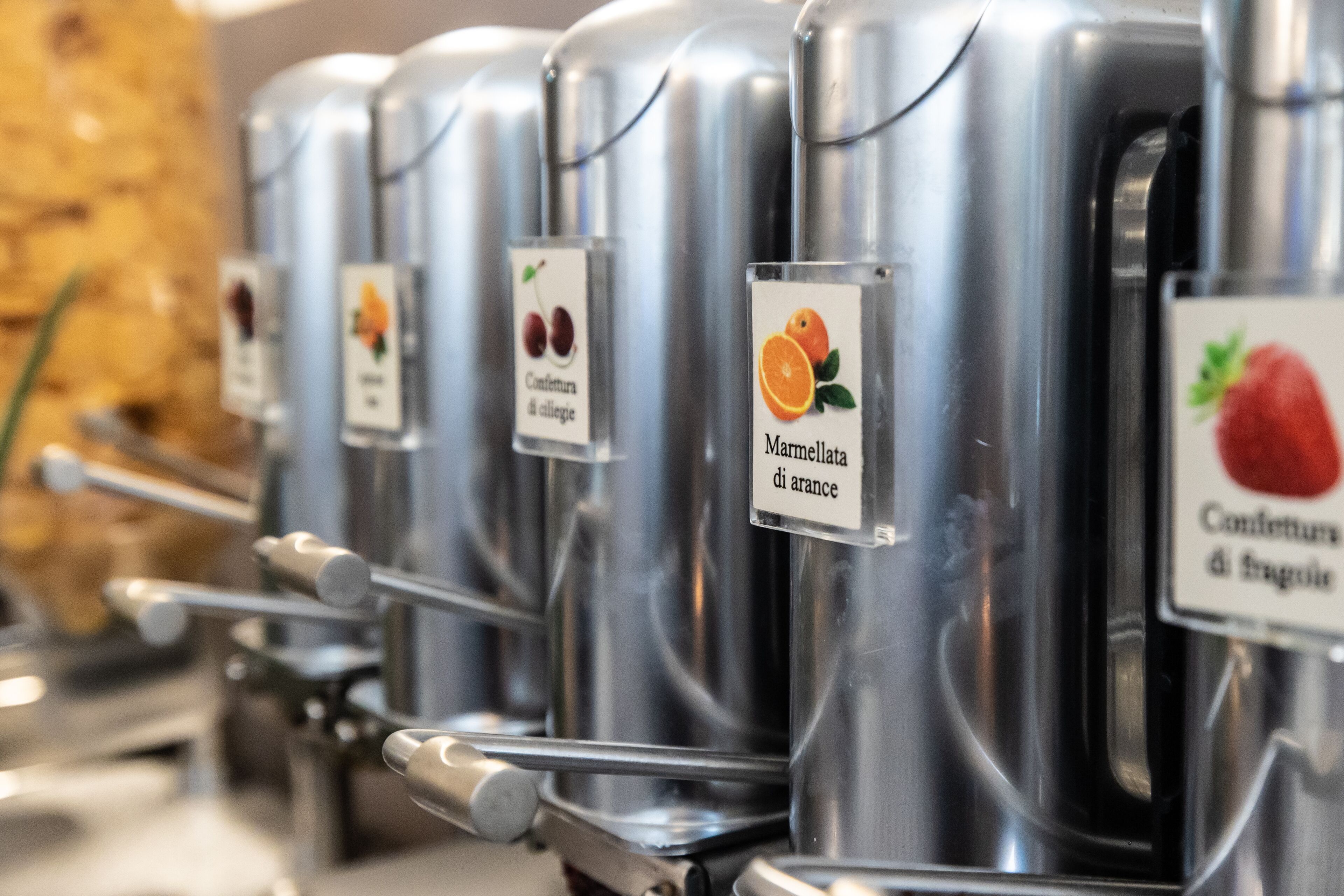 Dispensadores de acero inoxidable con etiquetas para distintos tipos de mermelada.