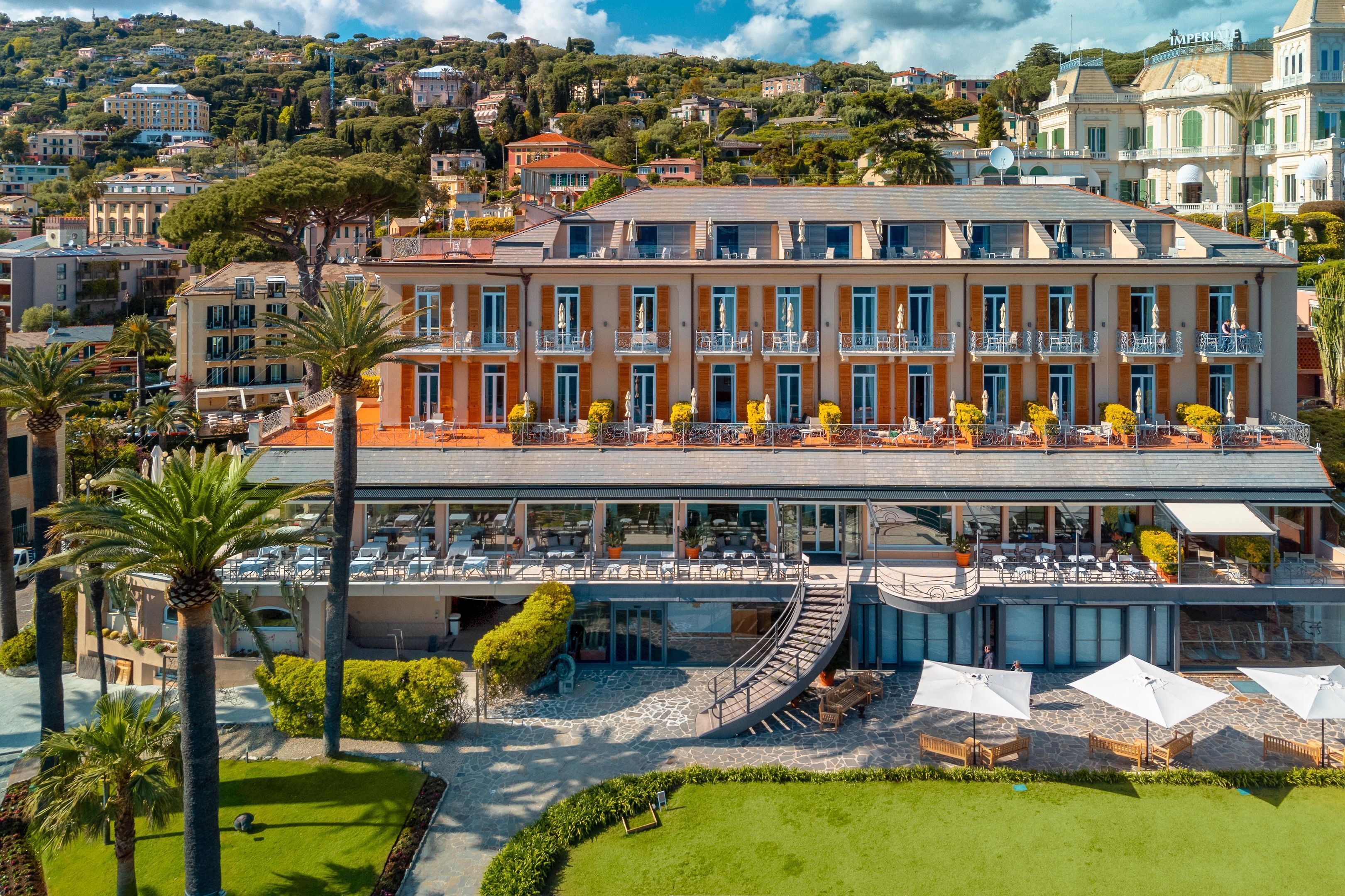 Un hotel con varios pisos, zonas de estar al aire libre y un patio ajardinado.