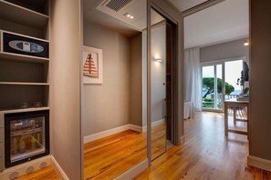 Een moderne hotelkamer met een houten vloer, een glazen schuifdeur naar een balkon, een in de muur ingebouwde haard en een ingelijste foto aan de wand.