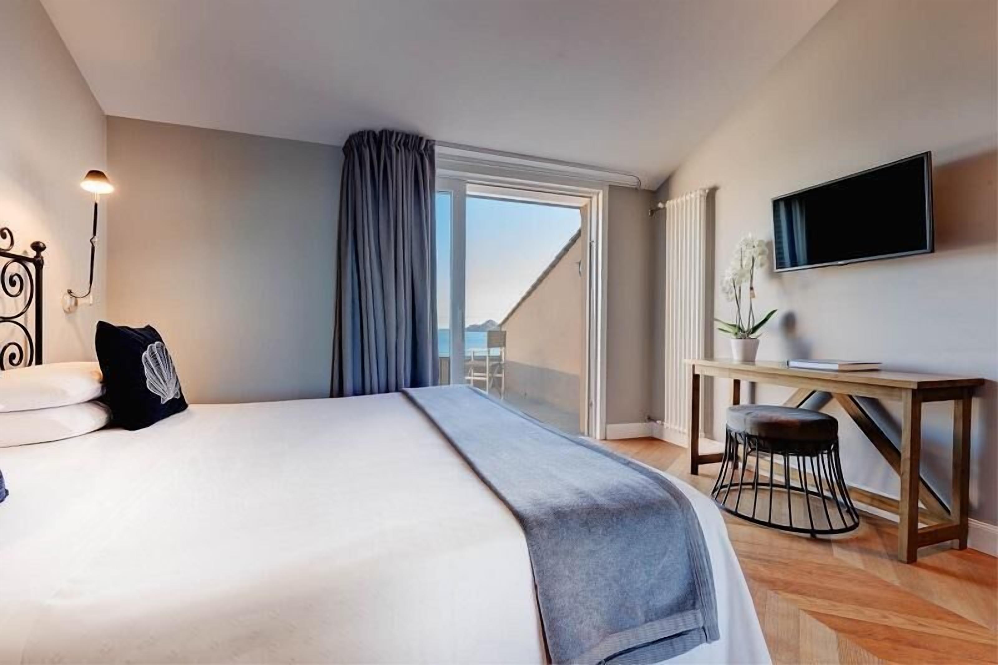 Een moderne hotelkamer met een groot bed, een bureau, een stoel, een televisie en uitzicht op de omgeving.