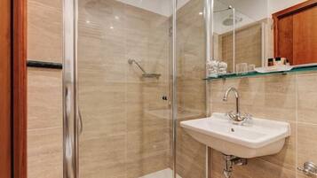 A modern bathroom with a glass-enclosed shower, a white sink, and a wooden cabinet above the mirror.