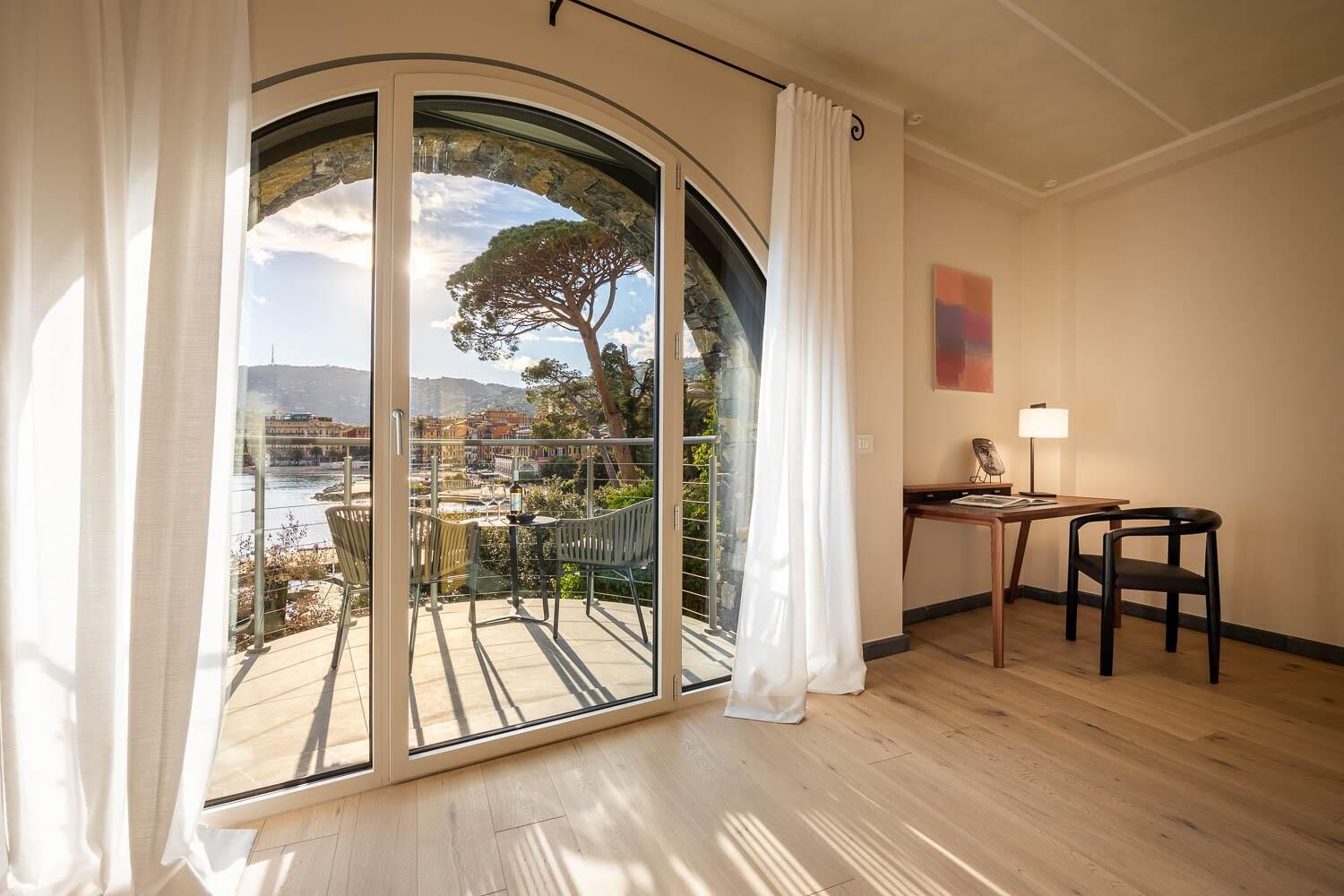 A room with a large sliding glass door leading to an outdoor terrace with a view of a tree and a cityscape.