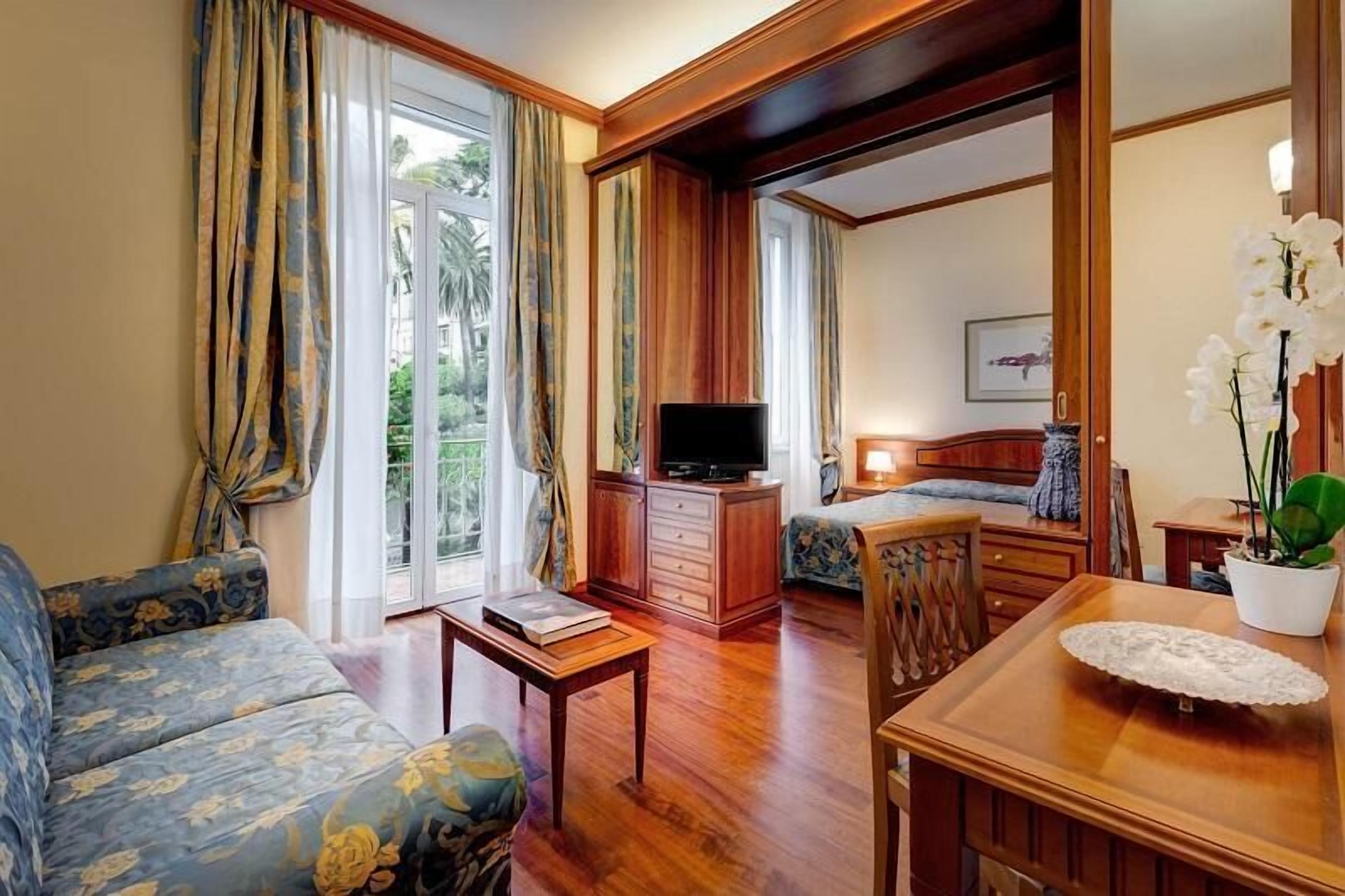 Una habitación de hotel con sofá, televisión, escritorio y cama.