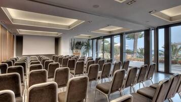 A conference room with rows of chairs, large windows, and a modern ceiling design.
