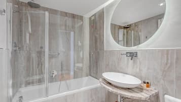 Een moderne badkamer met een douchecabine van glas, een vrijstaand bad en een marmeren wastafelmeubel met een wastafel.