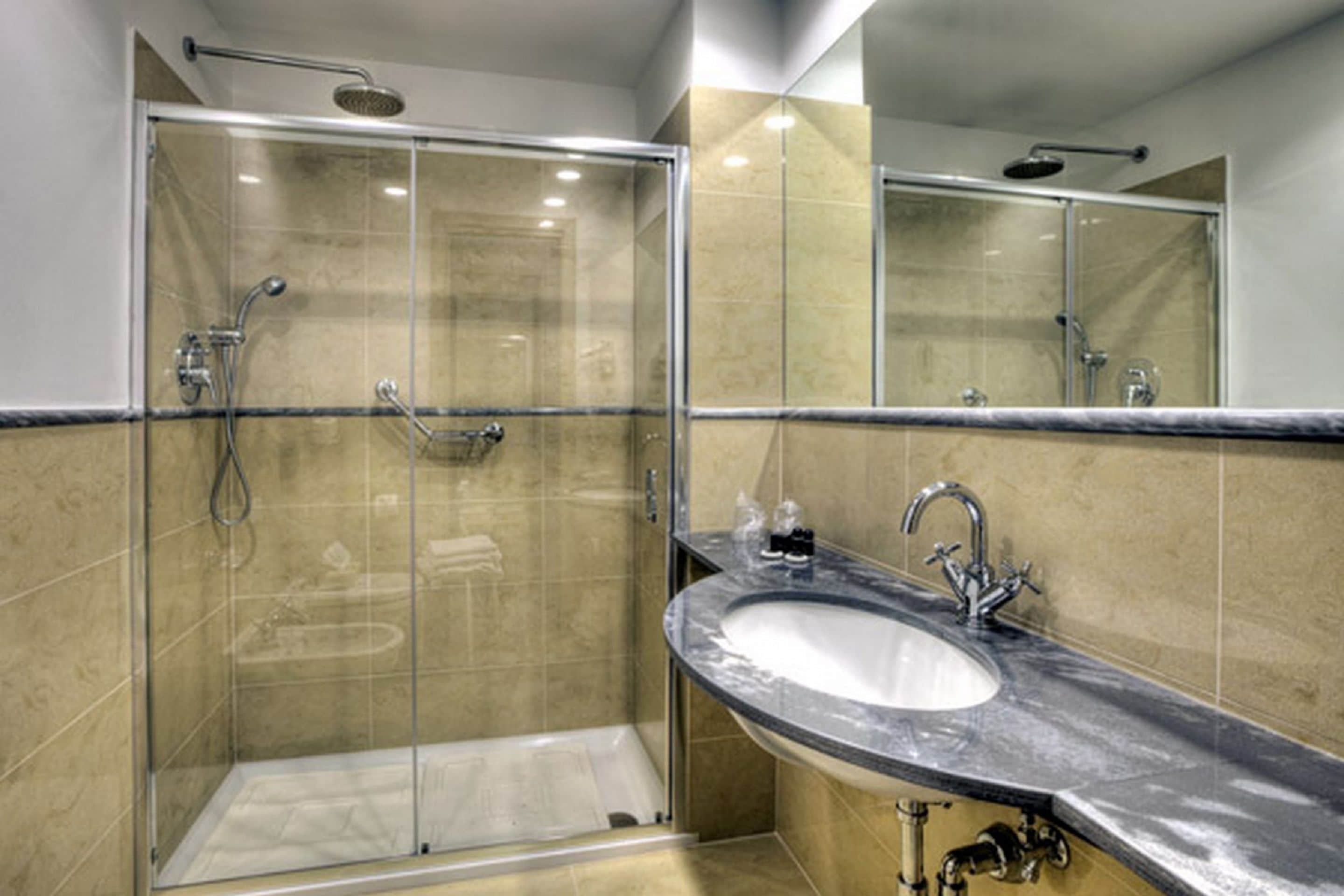 A modern bathroom with a glass-enclosed shower, a marble sink, and a large mirror.