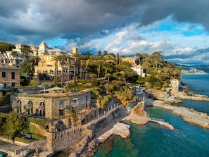 Un pueblo costero con edificios históricos de piedra, un puerto deportivo y un litoral rocoso.