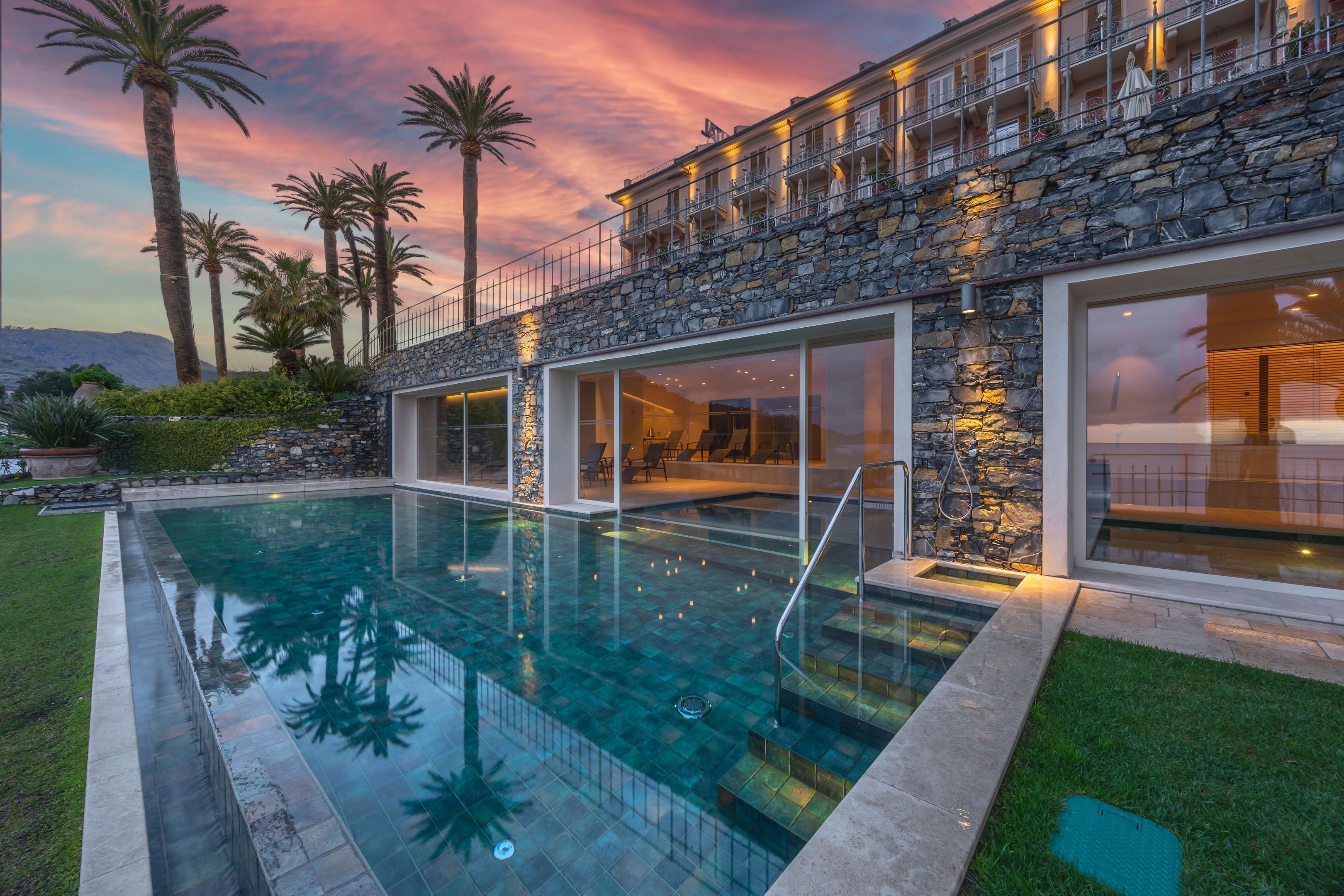 A modern house with a swimming pool, stone facade, and large windows.