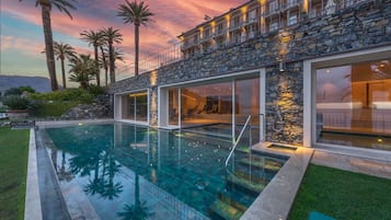 Una casa moderna con piscina, fachada de piedra y grandes ventanales.