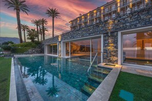 Een modern huis met een zwembad, een gevel van natuursteen en grote ramen.
