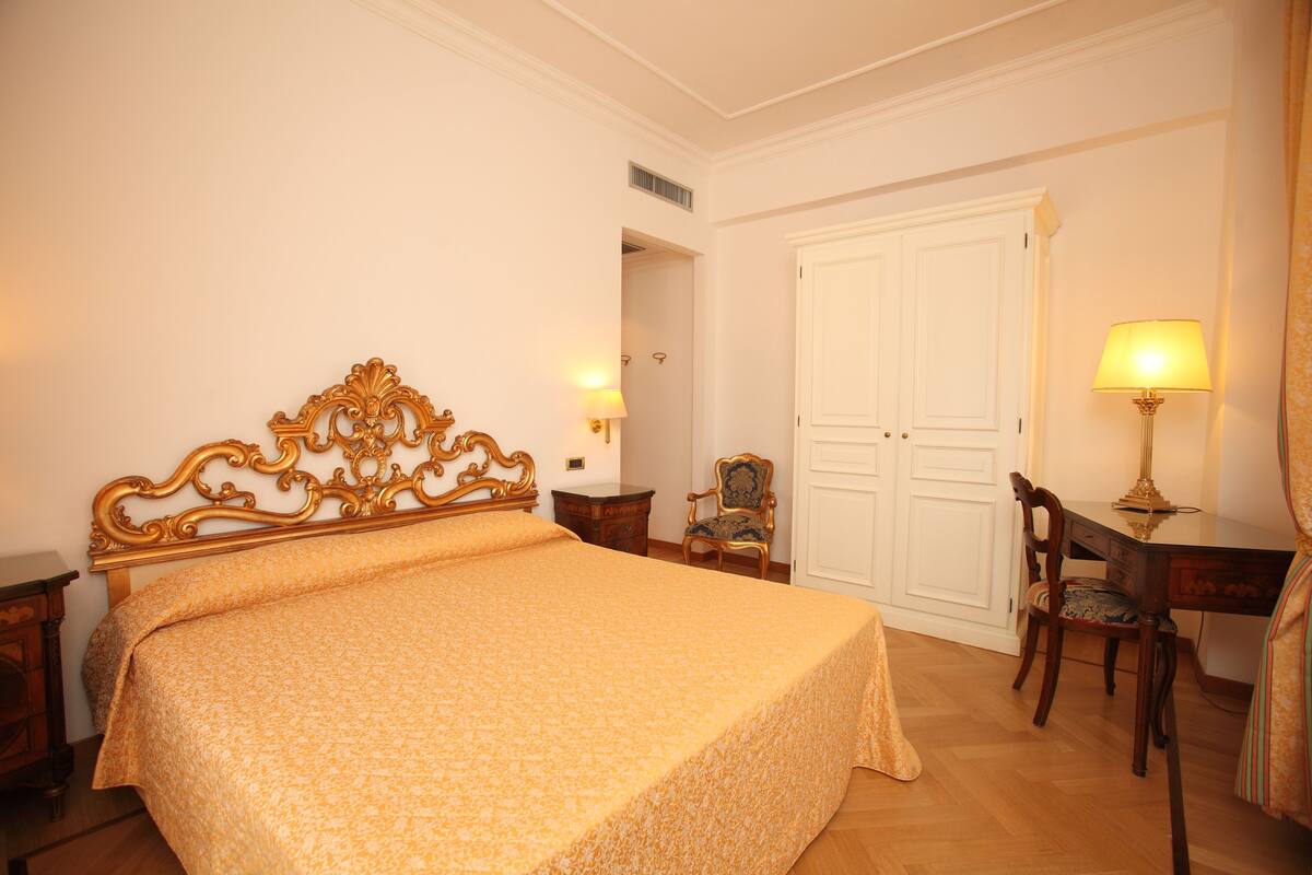 Une chambre à coucher avec un grand lit, un bureau, une chaise et une armoire.