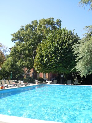 Una piscina al aire libre, sillones reclinables de piscina