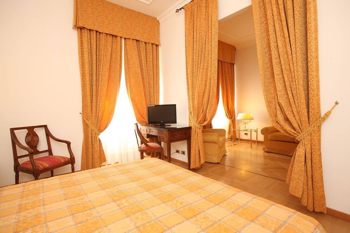 Une chambre d’hôtel comprenant un lit, un bureau avec une télévision, une chaise et un canapé.