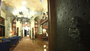Un vaste hall agrémenté de lustres somptueux, d’un tapis à motifs et d’une architecture classique.