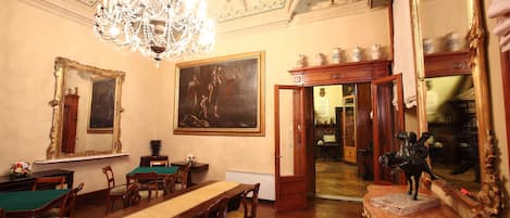 Un comedor con una larga mesa de madera, sillas, una araña y un cuadro grande en la pared.