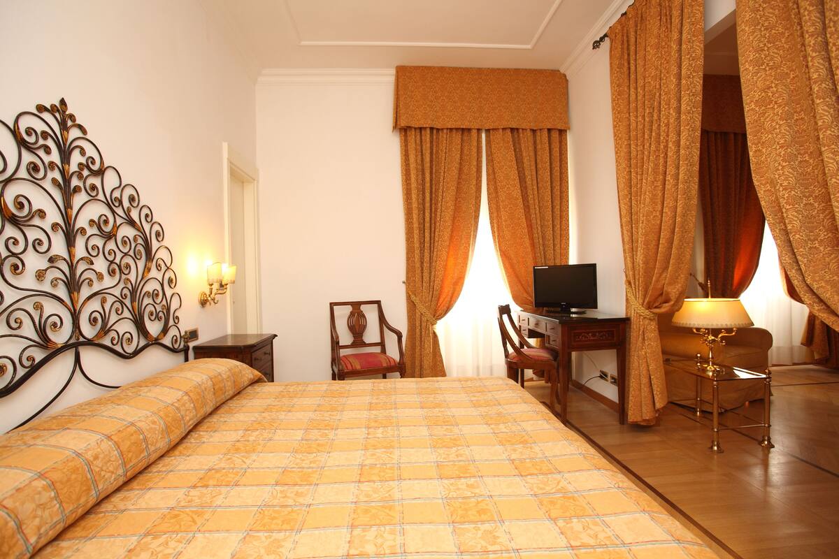 Une chambre d’hôtel comprenant un lit, un bureau avec une télévision, une chaise et une lampe.