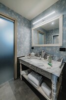 Un baño con tocador de mármol, un espejo grande y un perchero para toallas.