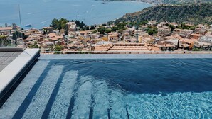 A pool with clear blue water and a view of a coastal town. - Hotel Villa Ducale (Taormina)