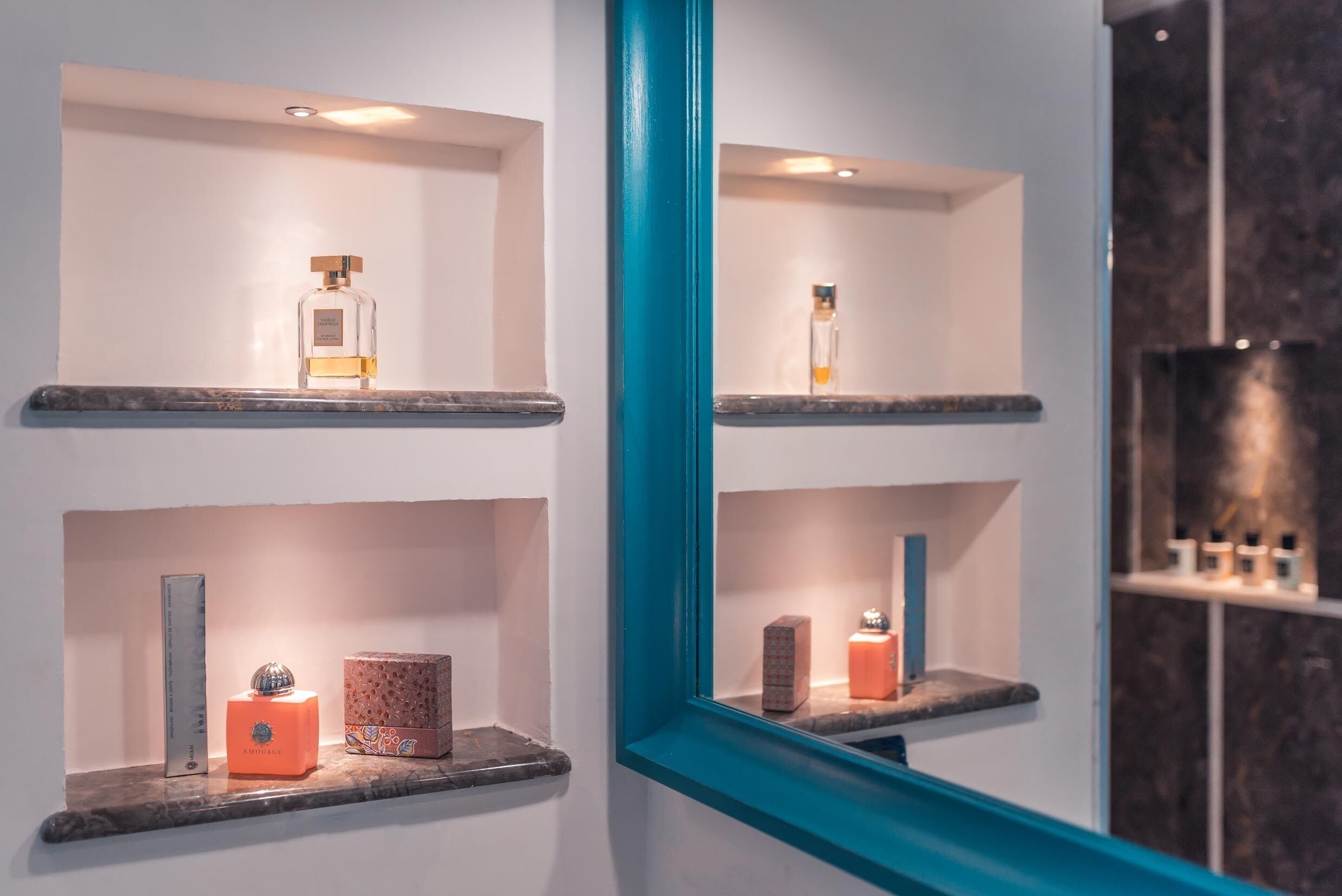 A bathroom with shelves displaying toiletries and a mirror reflecting the space.