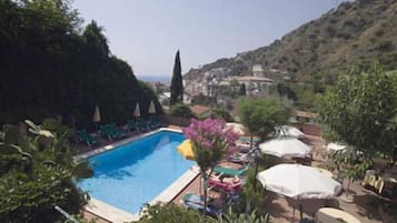 Una piscina al aire libre, sillones reclinables de piscina