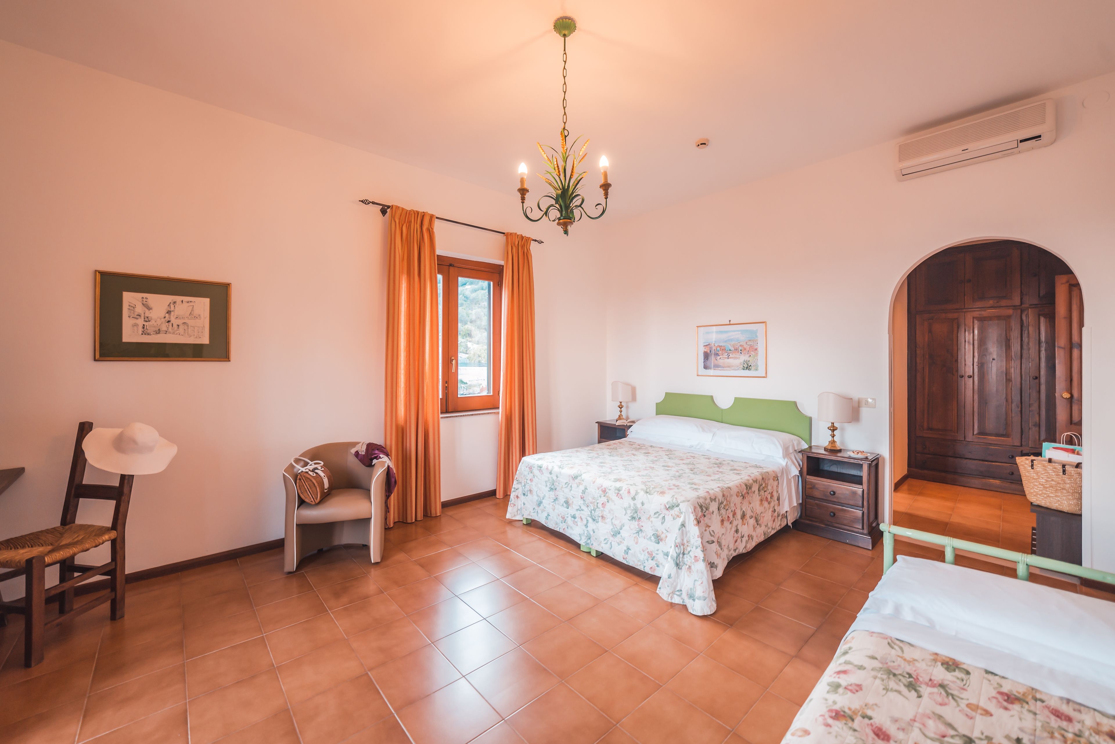 A bedroom with a bed, a chair, a nightstand, a lamp, a picture on the wall, and a door leading to another room.