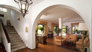 Amplia sala de estar con escalera, chimenea y un gran arco.