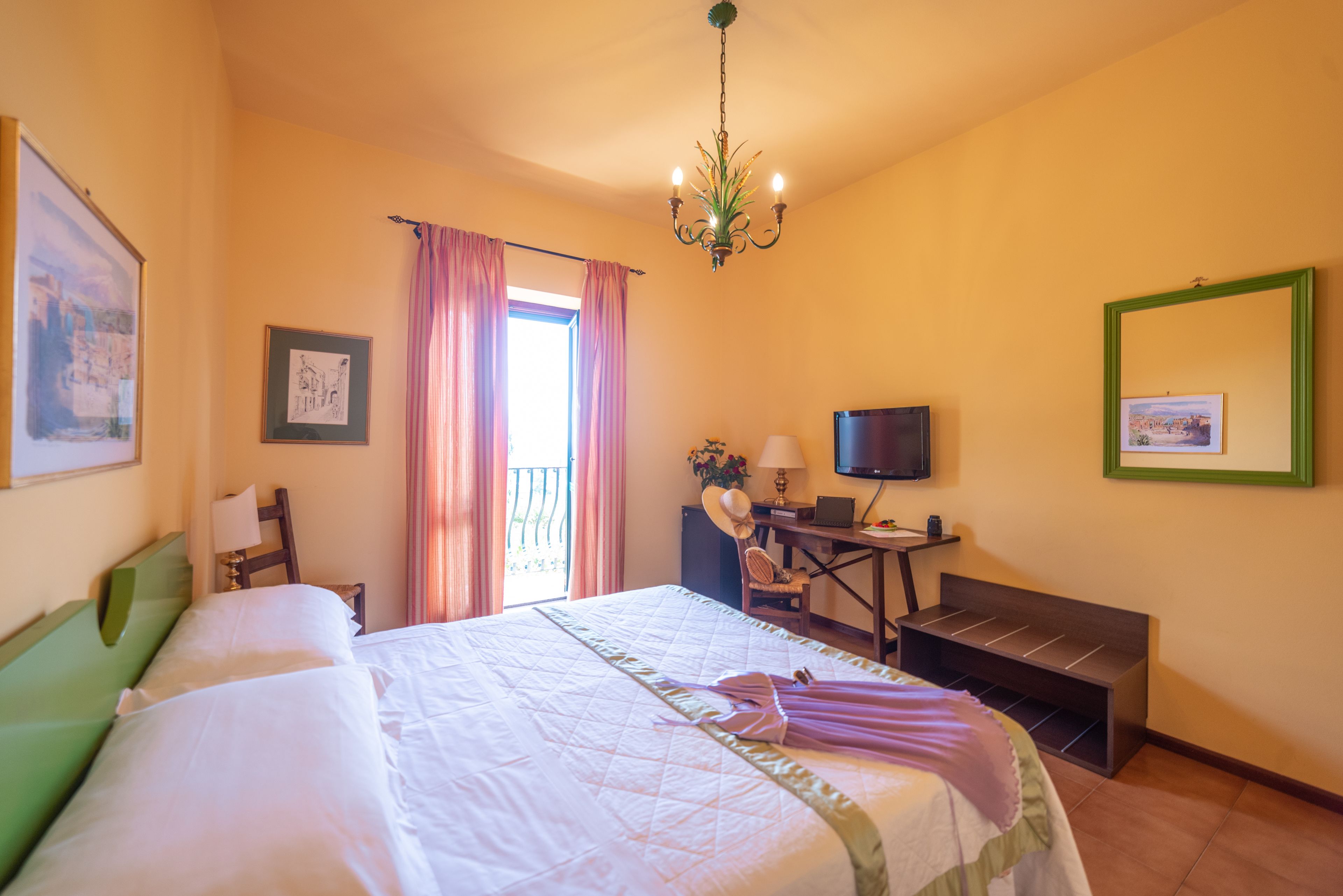 A hotel room with a large bed, a desk with a computer, a TV, and a chair.