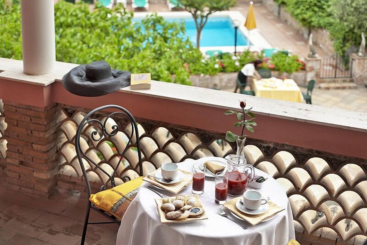 Une table mise pour le petit-déjeuner, avec vue sur une piscine et un espace verdoyant.