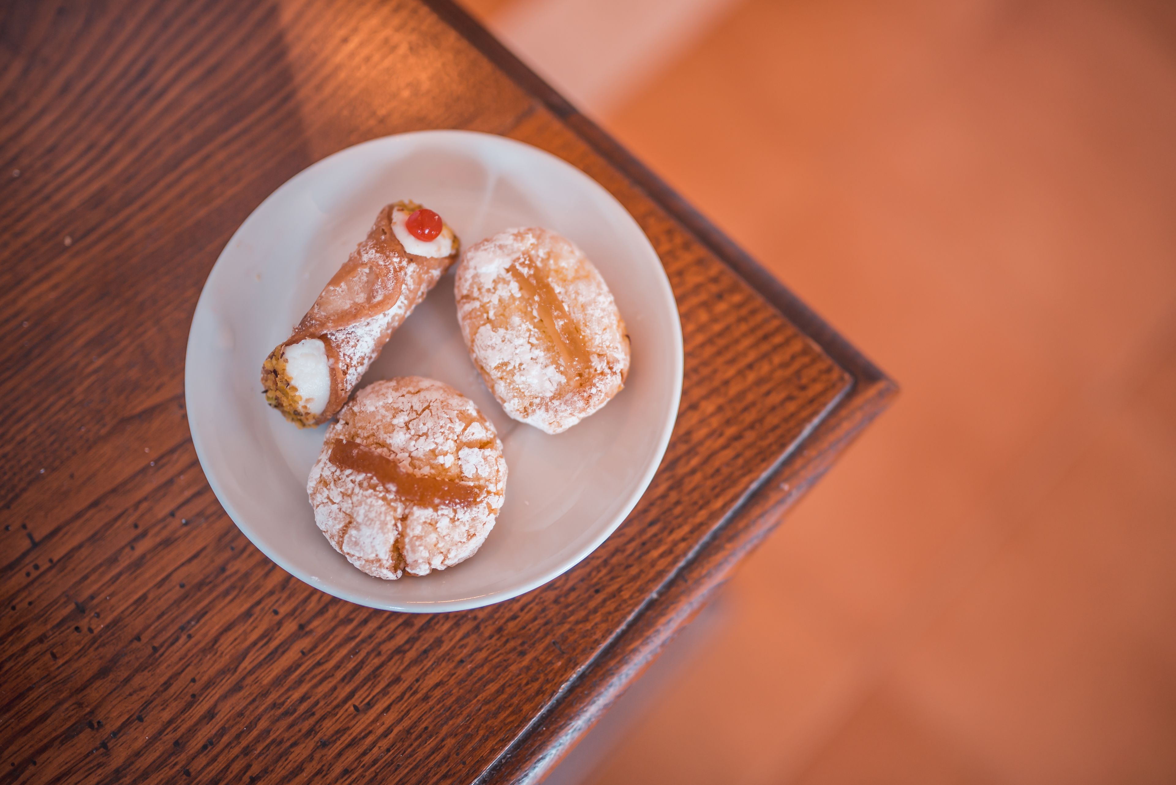 A plate with three pastries on a wooden table.