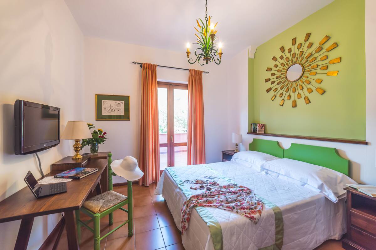 Une chambre d’hôtel équipée d’un lit, d’un bureau, d’une chaise, d’une télévision et d’un élément décoratif mural.