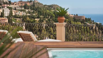A poolside area with a view of a coastal town, including buildings and a hill.