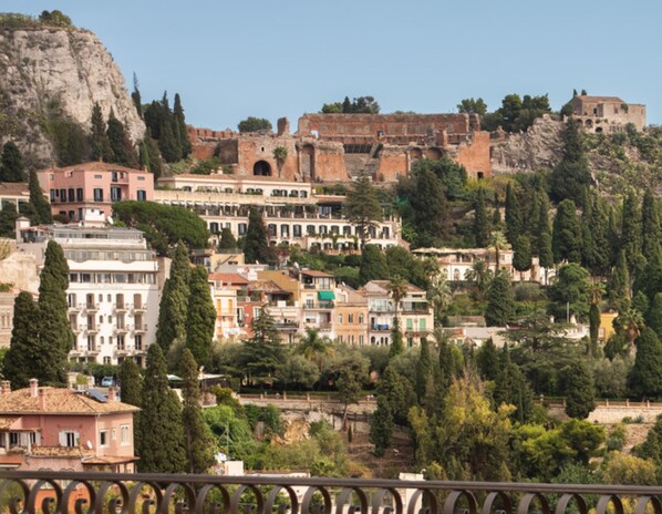A historic town with a prominent castle on a hill, surrounded by lush greenery and residential buildings. - San Domenico Palace, Taormina, A Four Seasons Hotel (Taormina)