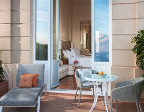 Relax on the balcony with a comfortable seating area, featuring a lounge chair and wicker armchair.